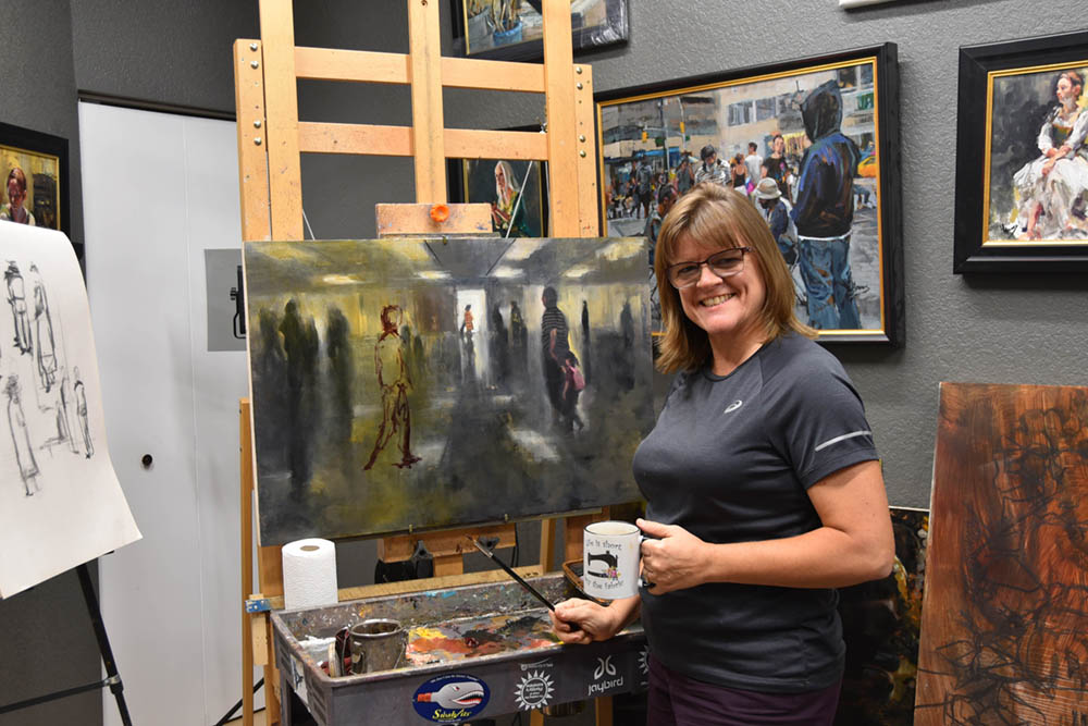Female artist in her studio in front of a painting on an easel