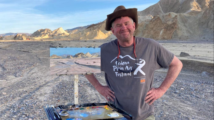 Male artist painting outdoors in the desert