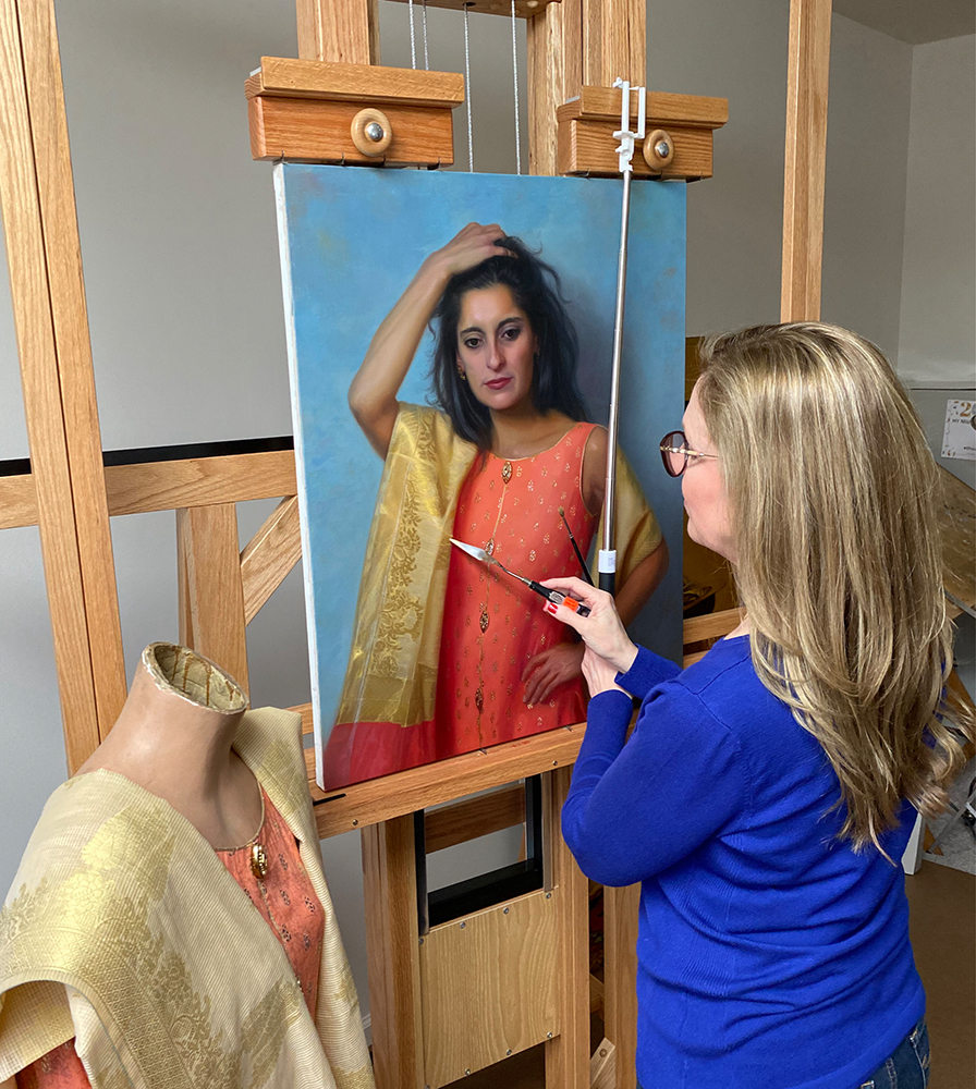 Female artist painting a portrait of a woman on an easel in her studio