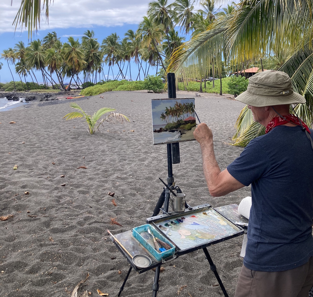 Male artist painting on the beach in Hawaii
