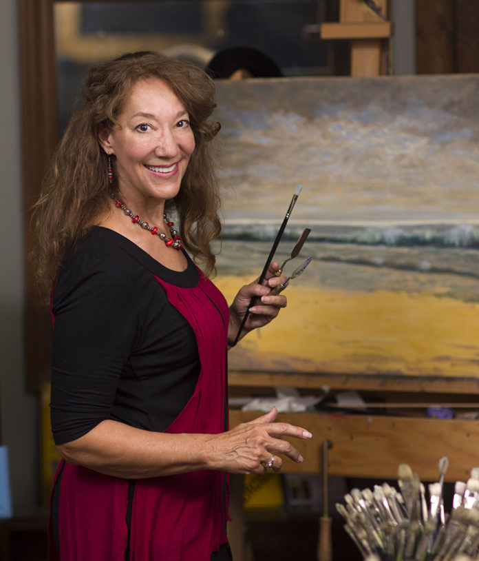 Female artist in her studio in front of one of her paintings on an easel