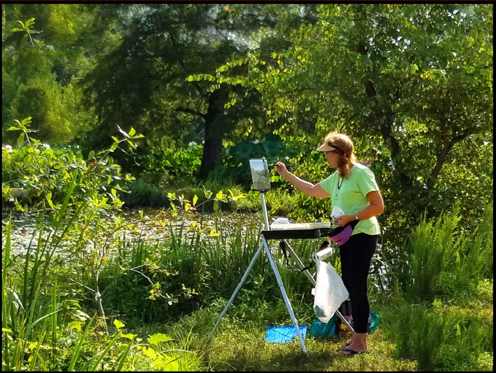 Female artist painting outdoors in a garden