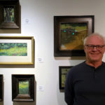 Artist Spotlight: Ray Hassard Male artist standing in front of his work in a gallery