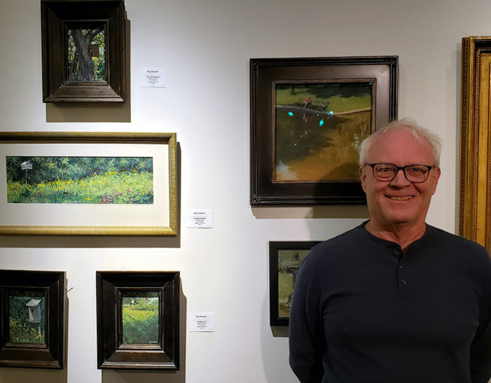 Male artist standing in front of his work in a gallery