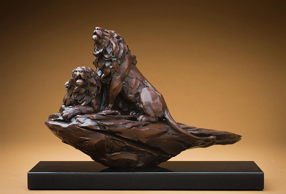 Bronze sculpture of two male lions on a rock