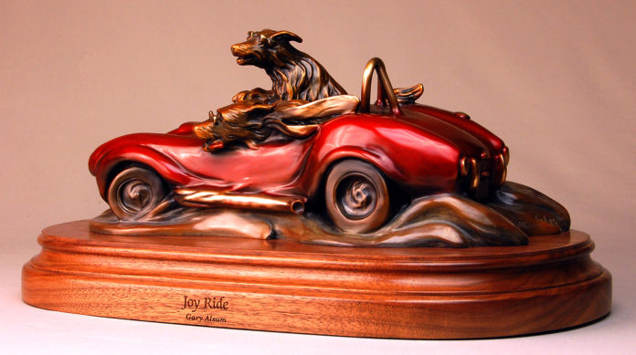 Bronze sculpture of dogs driving in a red racing car