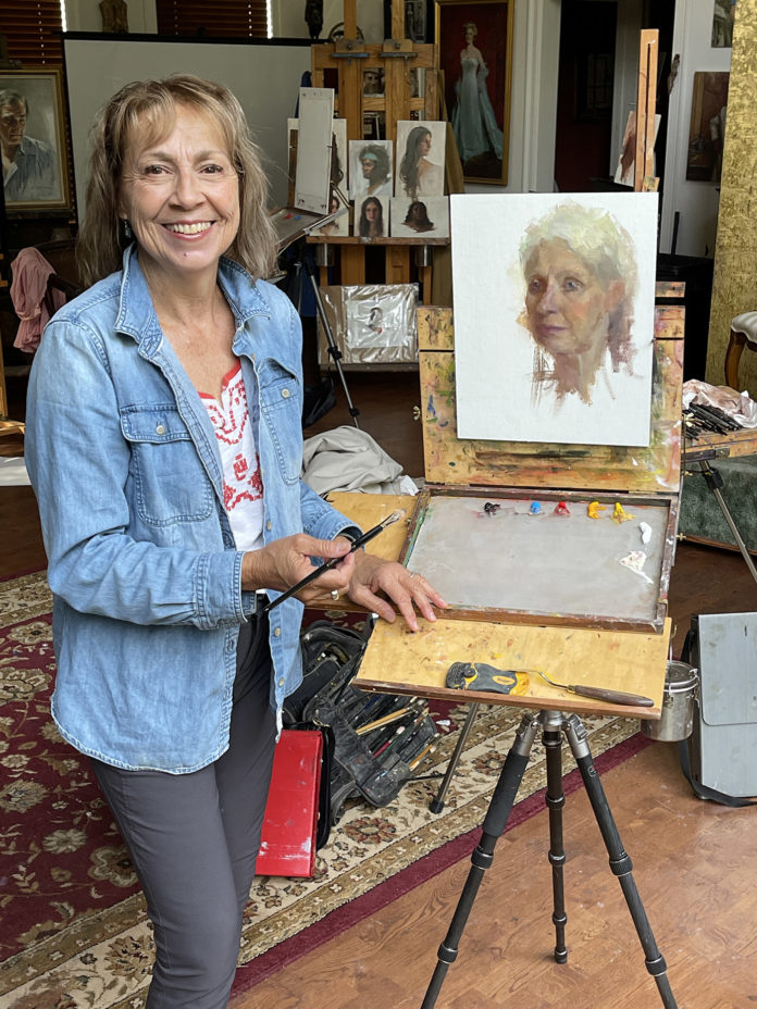 artist johanne mangi smiling with her artwork, in studio