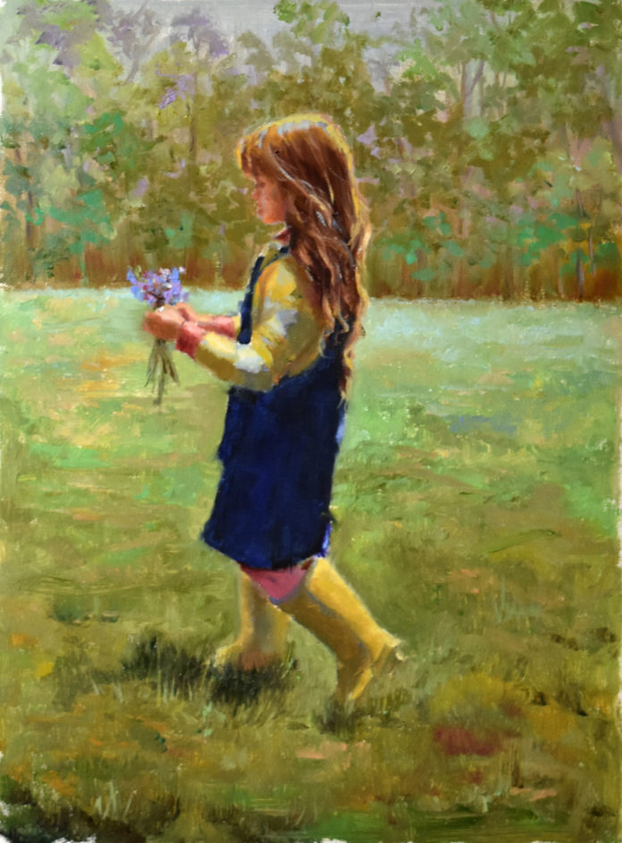 young girl walking through a field carrying flowers