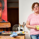 Artist Spotlight: Nadine Robbins artist posing for a photo with the portrait of her son
