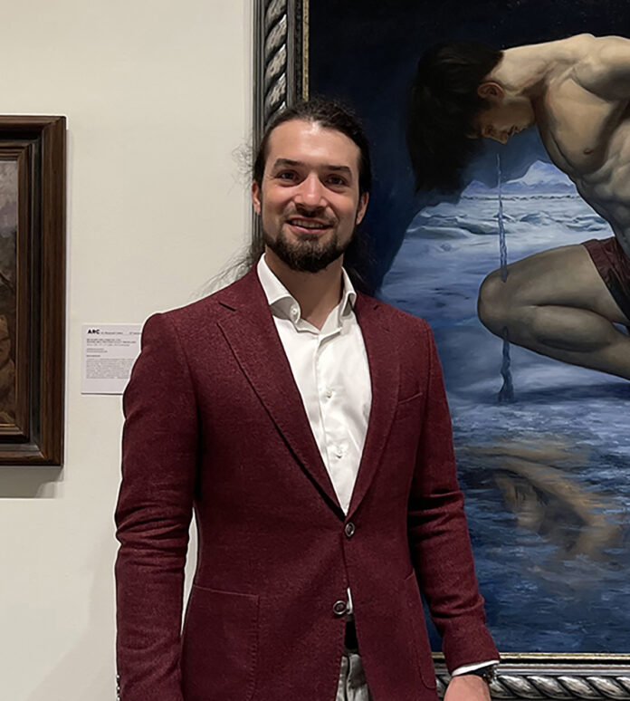 artist posing with his painting in Sotheby's exhibition