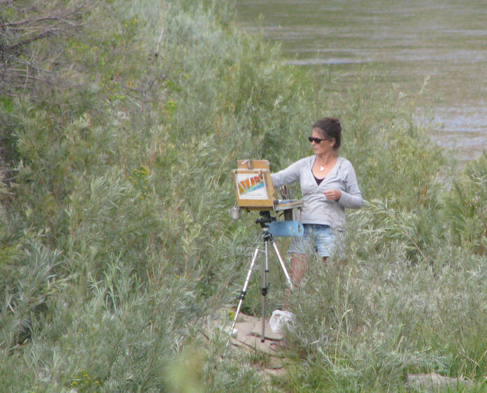 artist in a field, painting on location