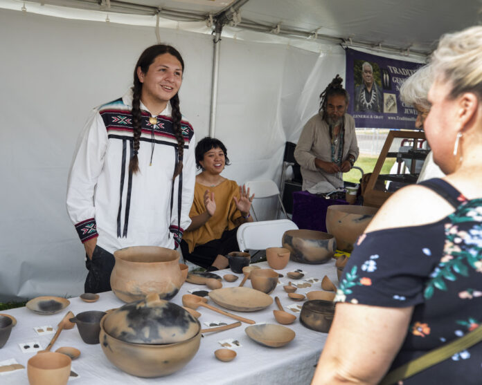 Artist Brandon Adriano Ortiz (Taos Pueblo) discussed his pottery with a market-goer at last year’s Eiteljorg Museum Indian Market and Festival in downtown Indianapolis.