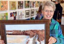 Artist Spotlight: Denise Antaya Artist holding up painting in a gallery