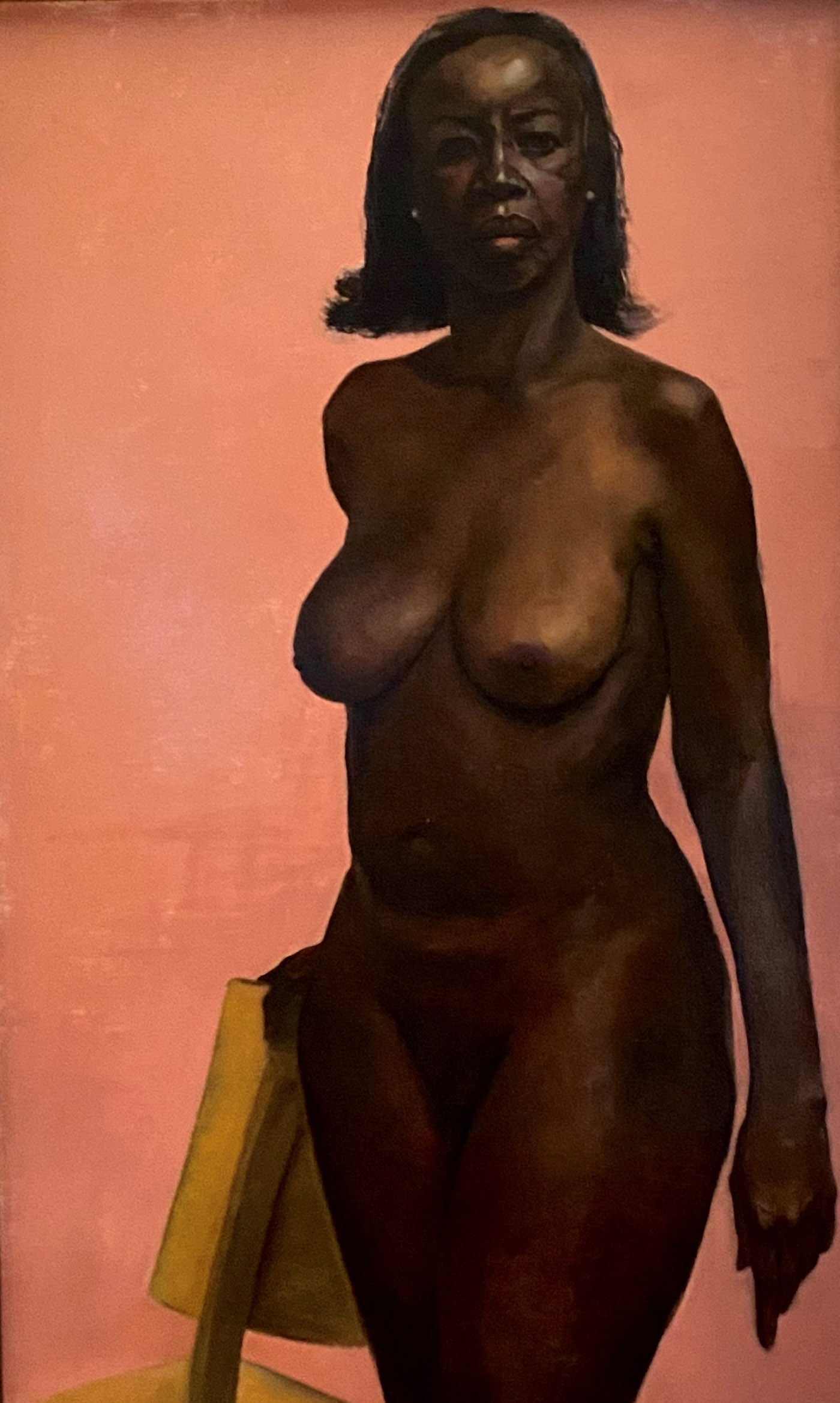 oil painting of nude African American, holding a chair, staring at the viewer
