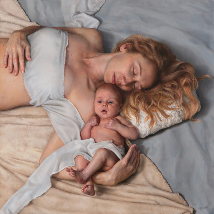 mother holding her baby close, laying on the bed