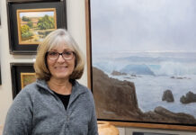 Artist Spotlight: Debra Joy Groesser Debra posing with her work hanging