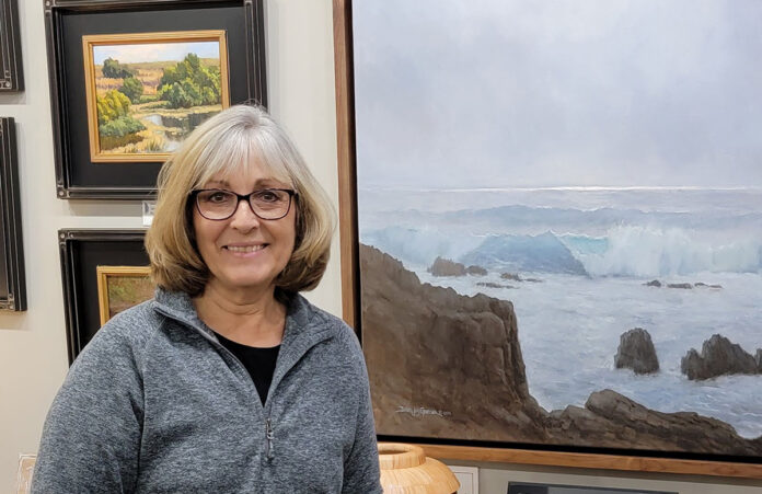 Debra posing with her work hanging