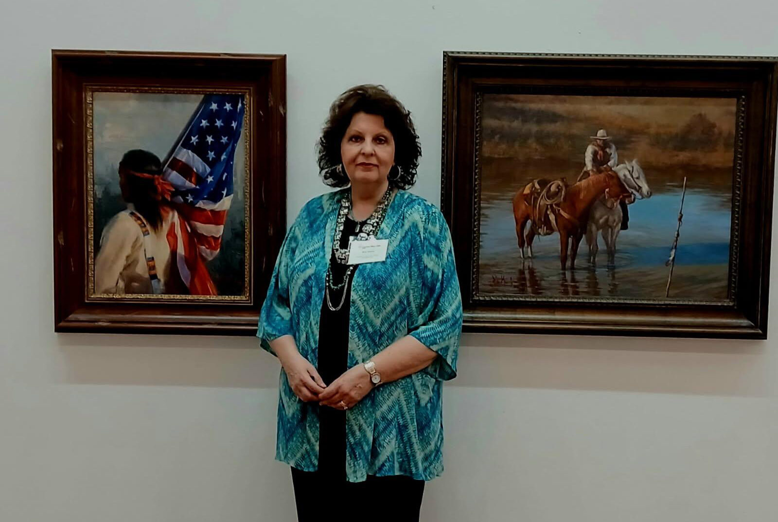 Artist Rita Morris with her two paintings, "Land That I Love" (left) and "Trouble Ahead."